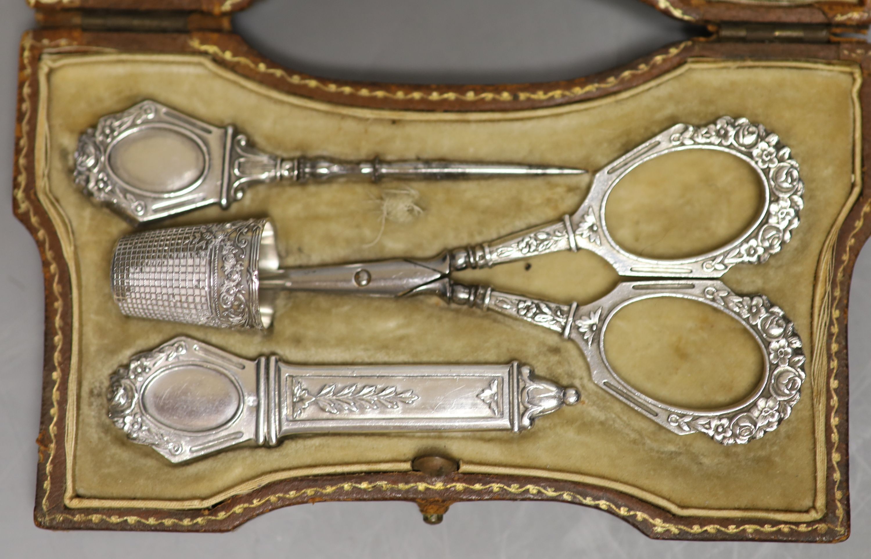 A cased 19th century French white metal necessaire, containing, scissors, needle case thimble etc, in gilt tooled leather case,13.1cm.